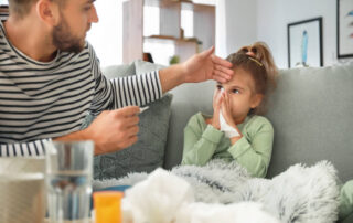 Father Taking Care Of His Daughter Ill With Flu At Home