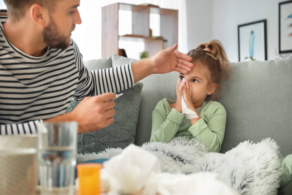 Father Taking Care Of His Daughter Ill With Flu At Home