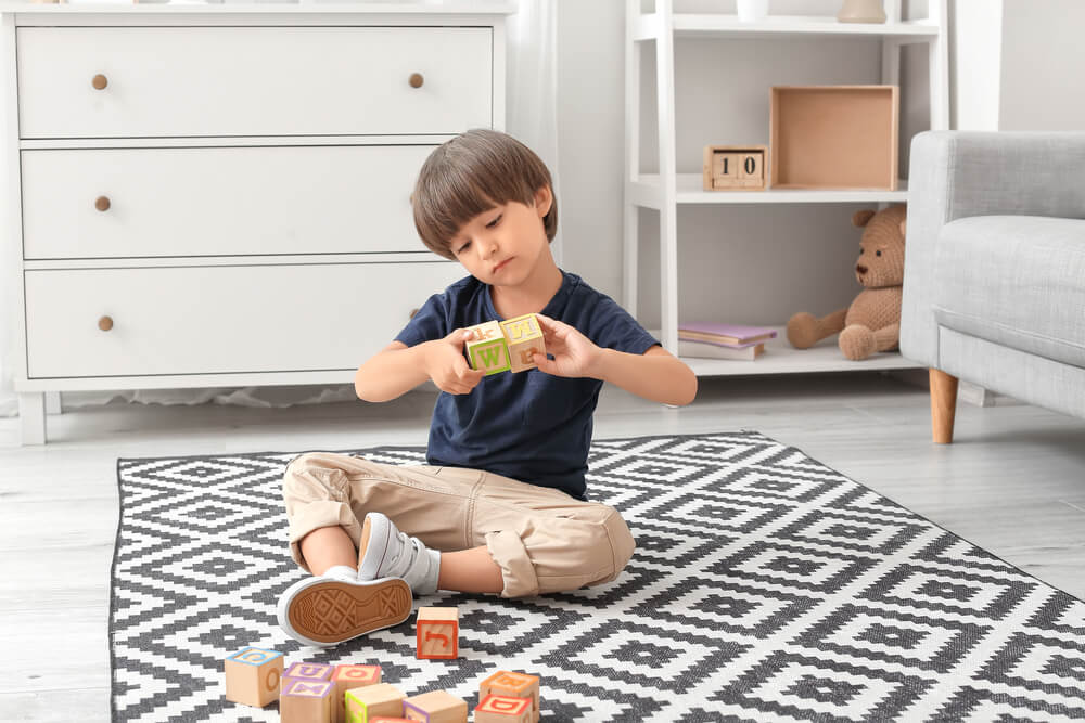 Little Boy With Autistic Disorder Playing With Cubes At Home