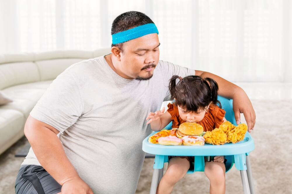 Overweight Father Gives Daughter Unhealthy Junk Food On High Chair At Home
