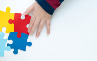 Top View Hands Of A Little Child Arranging Color Puzzle Symbol Of Public Awareness For Autism Spectrum Disorder