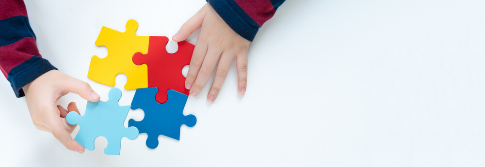 Top View Hands Of A Little Child Arranging Color Puzzle Symbol Of Public Awareness For Autism Spectrum Disorder