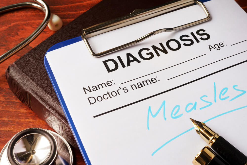 Medical form with the diagnosis of Measles on a table.