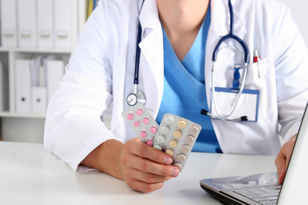 Female Doctor Hand Holding Bottle With Pills and Writing Prescription