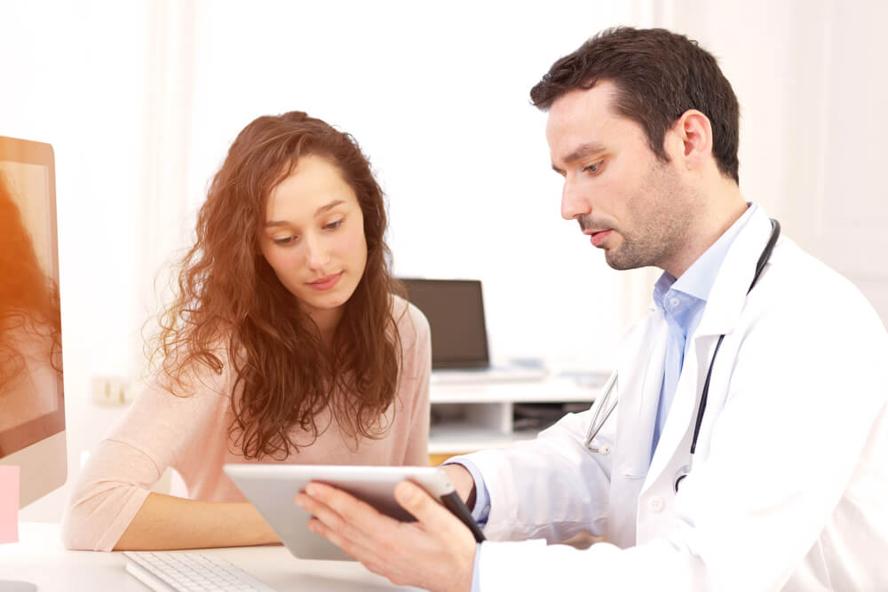 View of a Doctor Using Tablet to Inform Patient