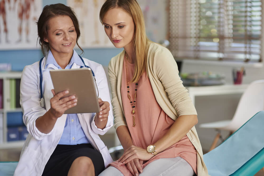 View of a Doctor Using Tablet to Inform Patient