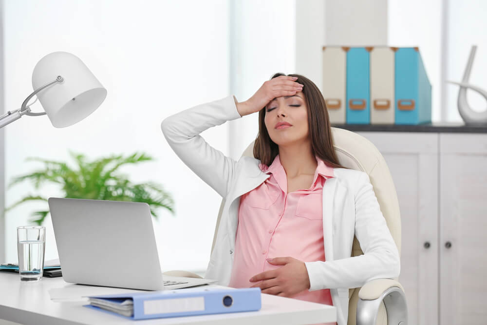 Tired Pregnant Woman Sitting at Her Workplace in the Office