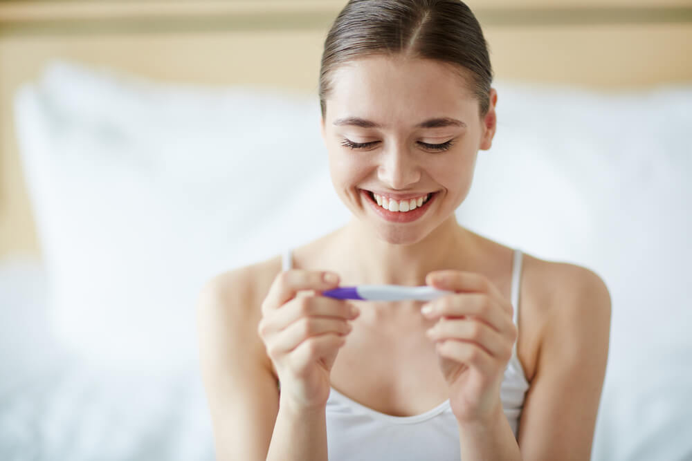 Young Woman Looking at Pregnancy Test in Happiness