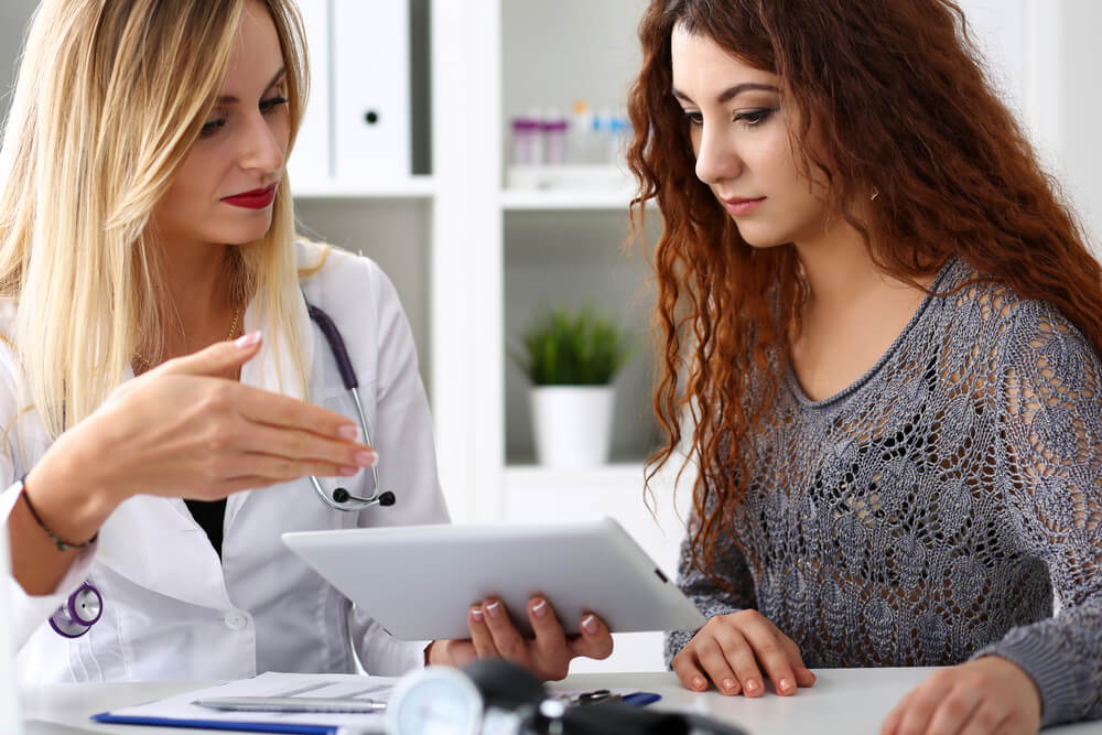 Beautiful Female Medicine Doctor Explain Diagnosis to Patient Holding and Showing Digital Tablet