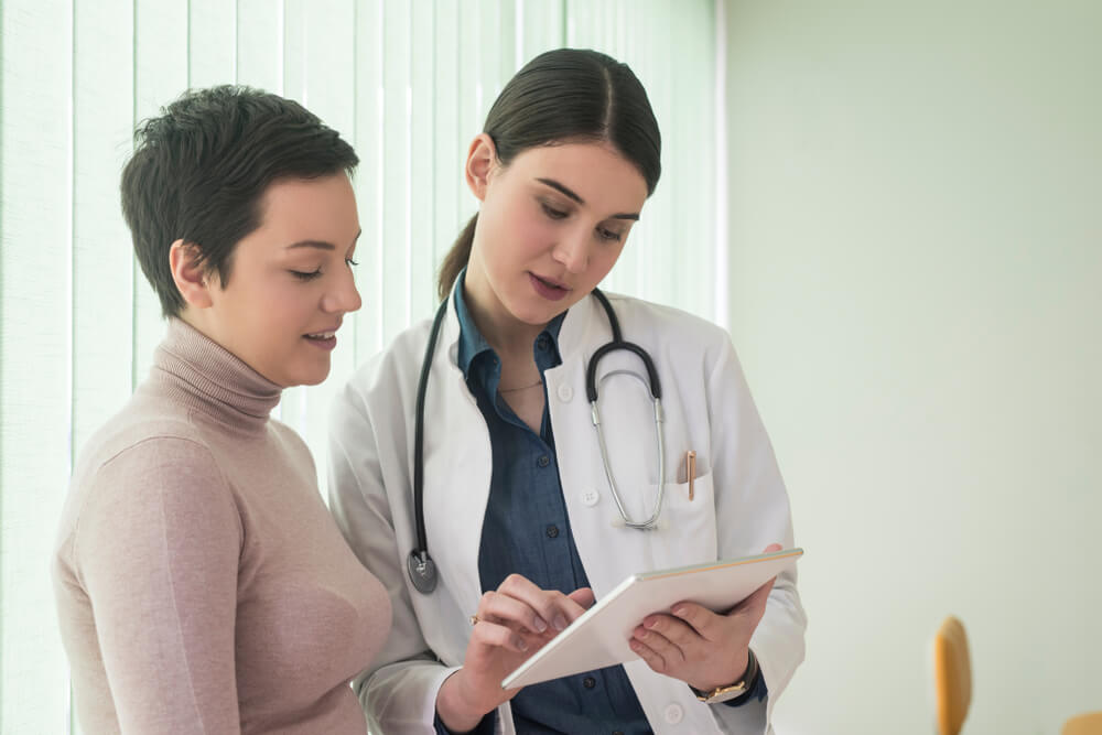 Woman Doctor and Her Patient Looking at Tablet Together.