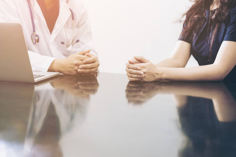 Doctor and Female Patient Talking on the Office Desk Showing Health Problem Communication Between Patient and Doctor.