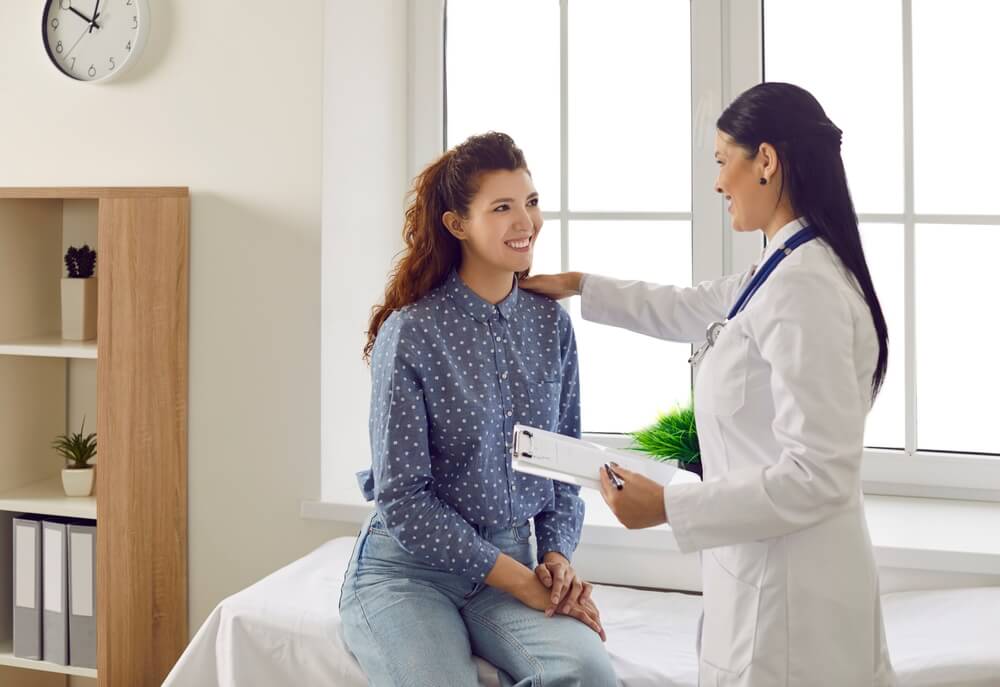 Friendly Smiling Female Doctor Touches Patient’s Shoulder and Tells Her Good News.