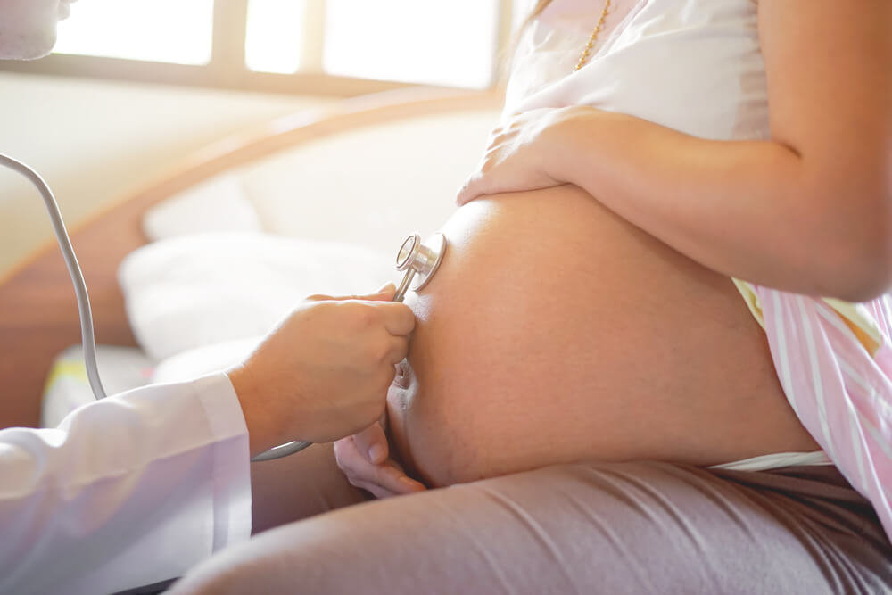 Healthcare and Medical Care Concept Close Up Male Doctor Hand Checking Up on Pregnant Woman, Using Stethoscope Checking Fetus Baby Infant Inside