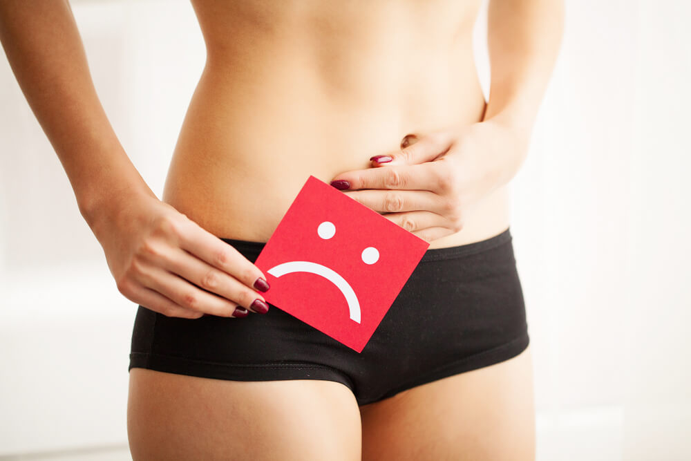 Vaginal or Urinary Infection and Problems Concept. Young Woman Holds Paper With Sad Smile Above Crotch