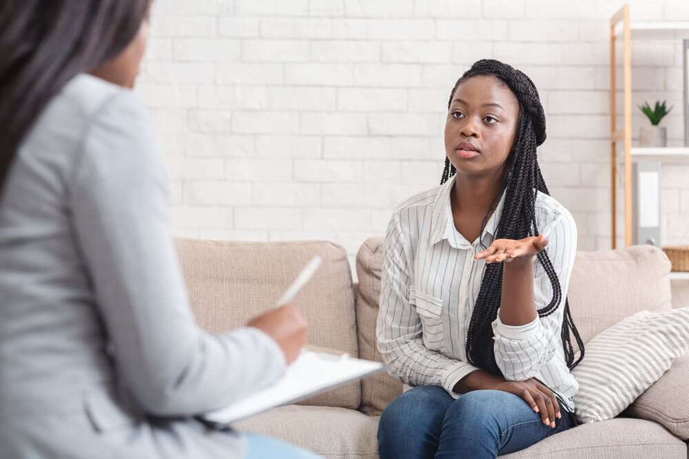 Psychotherapy Concept. Sad Afro Lady Sharing Her Problems at Counselor’s Office, Sitting on Couch and Emotionally Telling Something