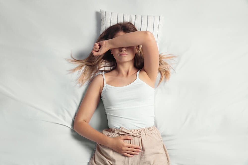 Young Woman Suffering From Menstrual Pain in Bed
