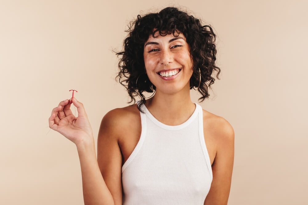 A young woman holding the copper IUD in her hand.