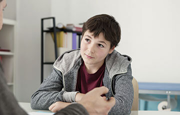 dark haired boy in grey hoodie having consultation with a doctor-1