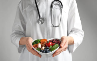 Doctor Holding Bowl With Products for Heart-Healthy Diet on Color Background, Closeup