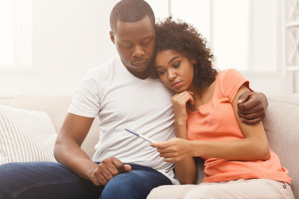 Sad Couple After Negative Pregnancy Test Result, Sitting on Couch at Home
