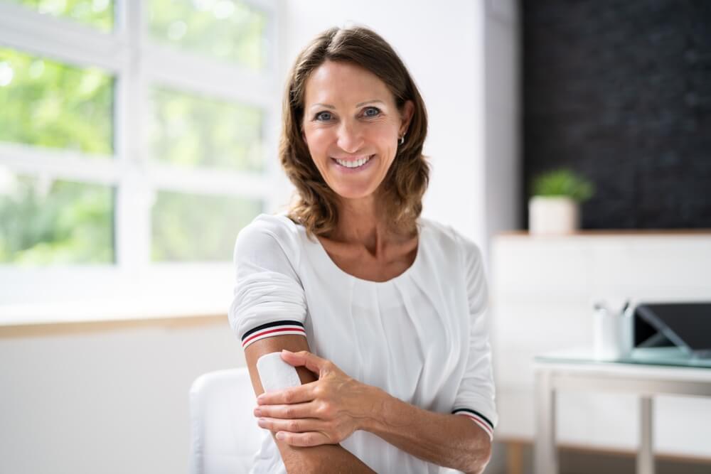 Woman Applying Patch On Her Arm At Home