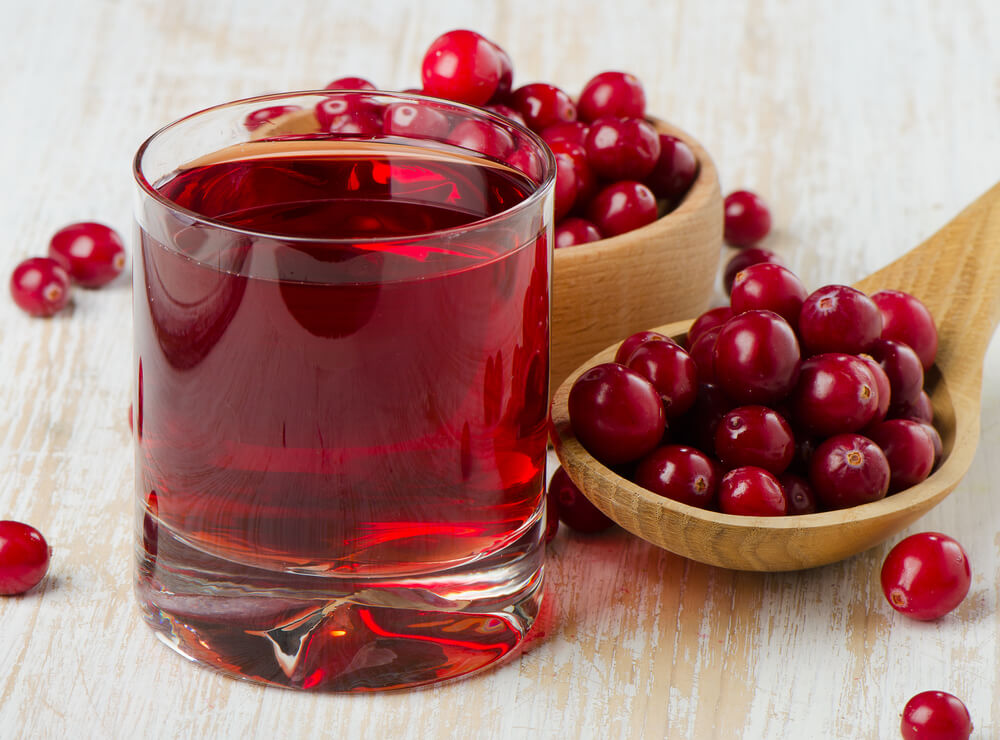 Cranberries in a Wooden Spoon and Glass of Juice