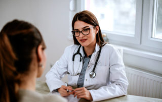 A Woman Sitting at a Table Talking to a Doctor.