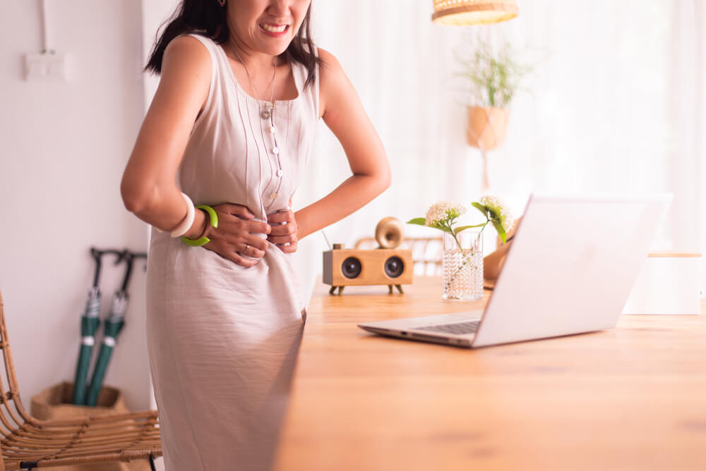 Woman Having Painful Stomach Ache During Working at Home, Period Cramps,Hands Squeezing Belly, Abdominal Pain