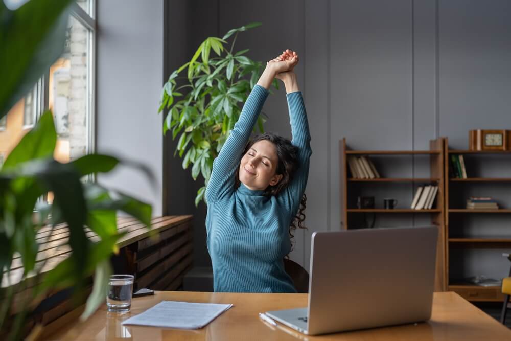 Happy Businesswoman Warming Up Body And Muscles At Workplace Feeling Satisfied With Work Done Smiling Female Employee Resting From Computer Scree