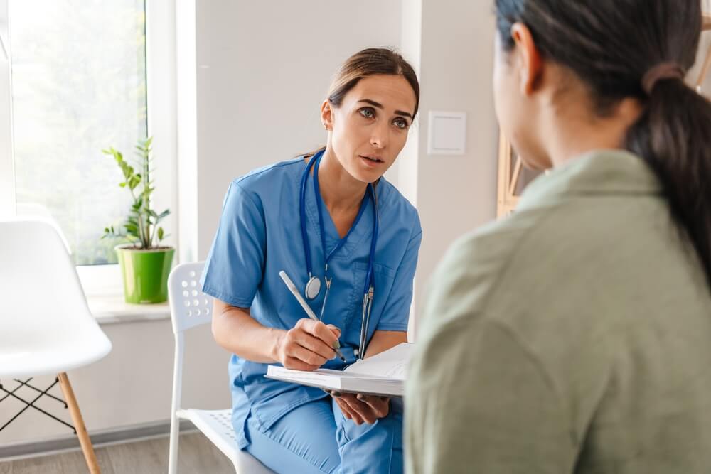 White Woman Doctor Talking With Patient While Working in Her Office Indoors