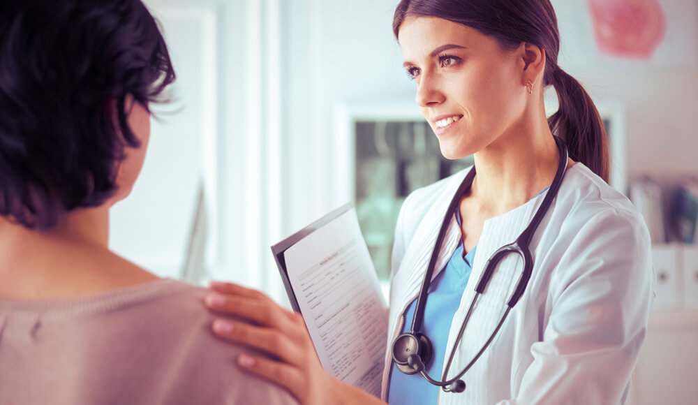 Medical Consultation. Female Doctor Holding a Patient by Her Shoulder, Soothing Her Fear