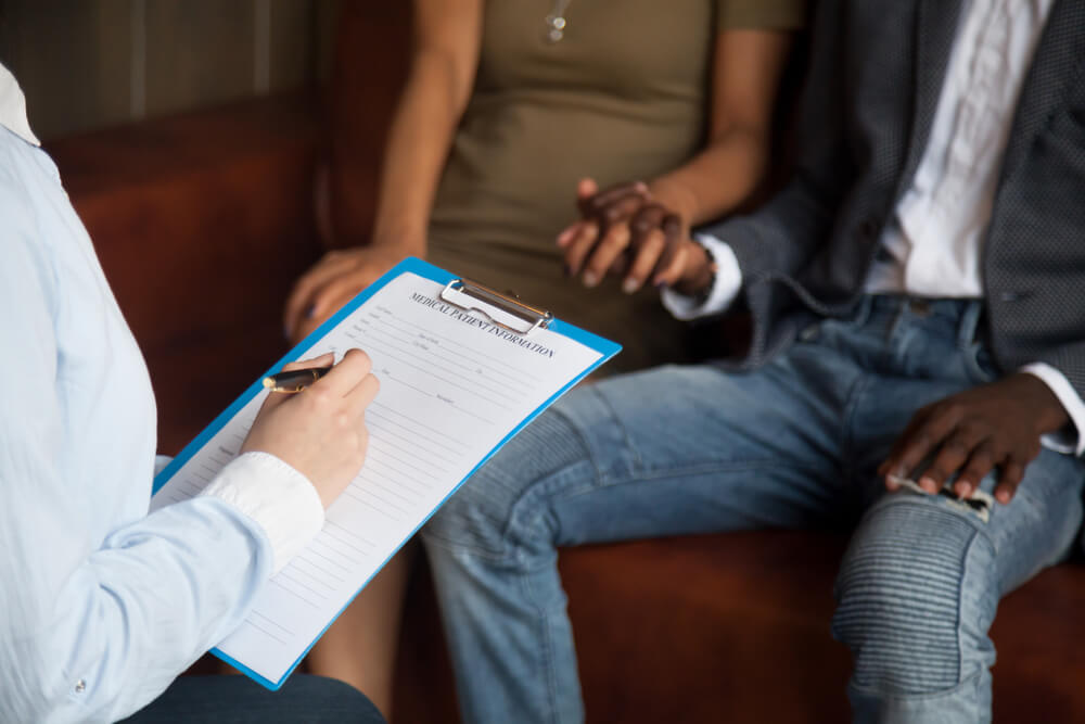 Female Doctor Consulting Young Couple Patients