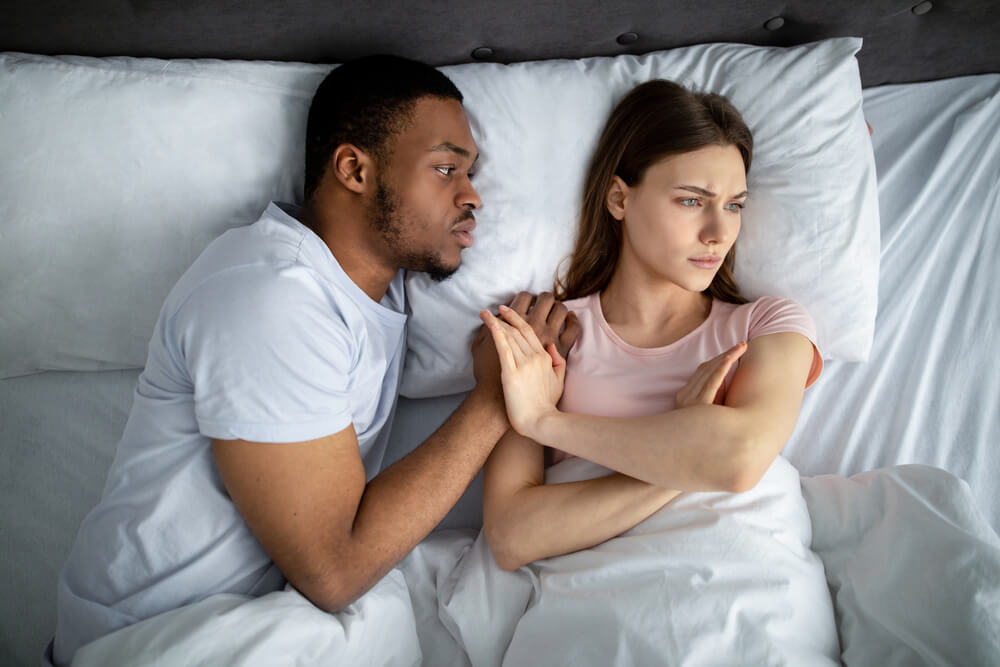 Guy Touching His Upset Girlfriend in Bed, Woman Refusing