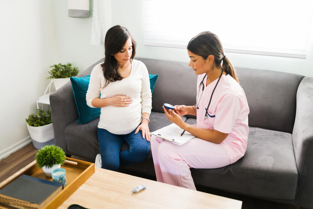 Professional Female Doctor Using a Monitor to Test the Blood Glucose of a Pregnant Woman