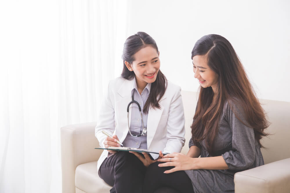 A Portrait of an Asian Female Patient Consulting With a Female Doctor