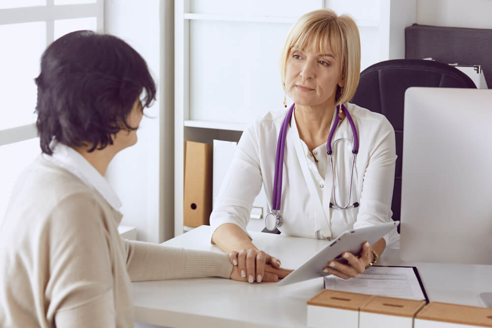 Doctor With Laptop and Pregnant Woman in Doctor’s Office