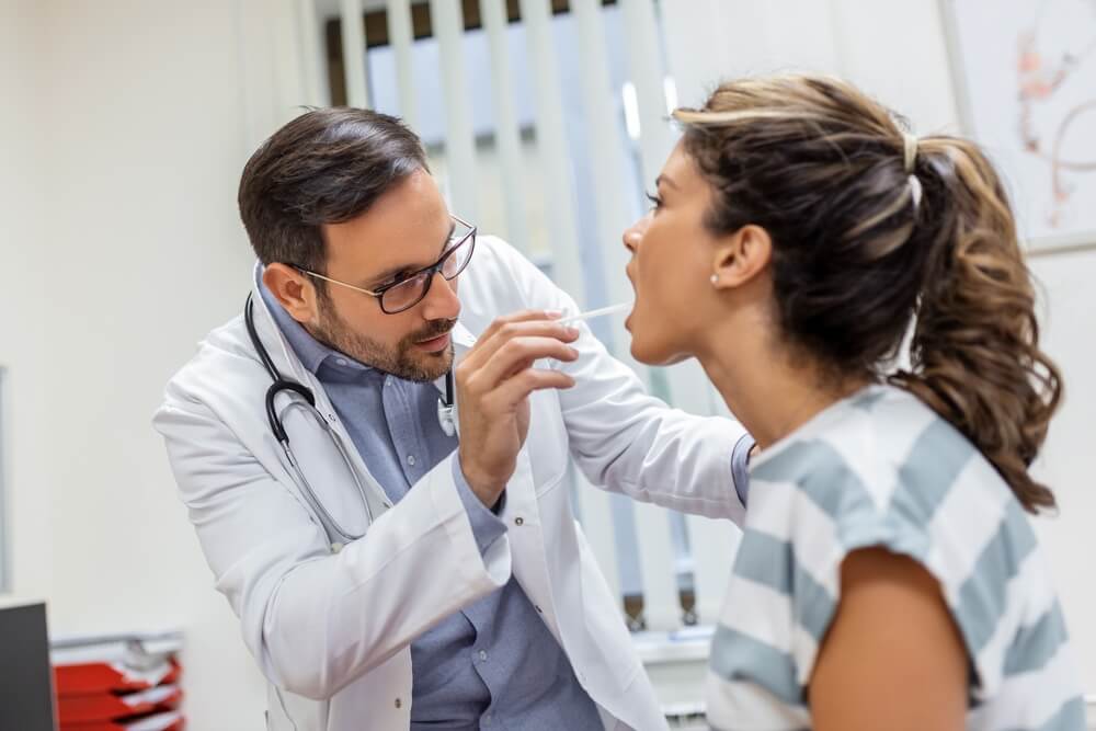 Doctor Using Inspection Spatula To Examine Patient Throat.