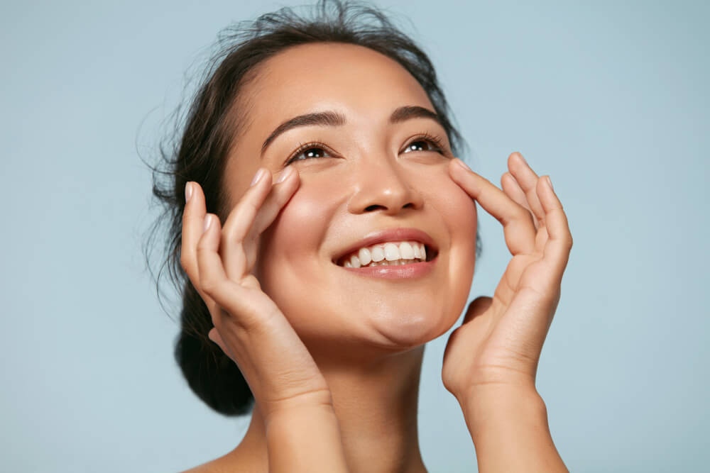 Woman With Beauty Face Touching Healthy Facial Skin Portrait.