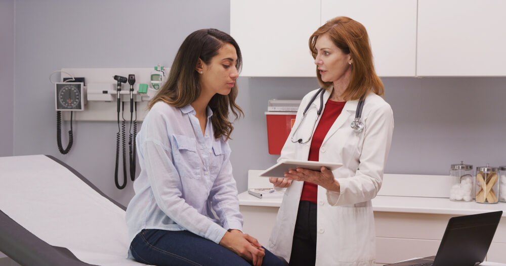 Young Latina Woman Having Check Up With Mid Aged Caucasian Doctor at Clinic