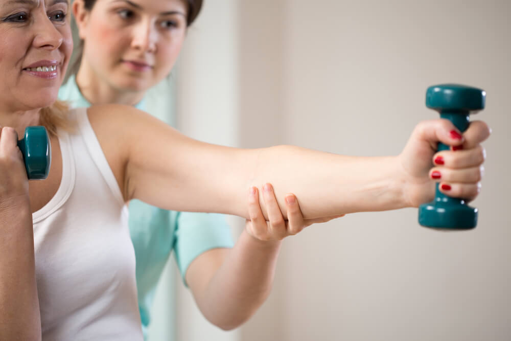 Woman Exercising With Dumbbells Insured by Physiotherapist