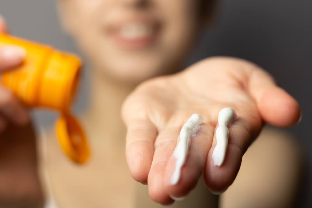 Young Woman Applying the Correct Amount of Sunscreen for Face and Neck