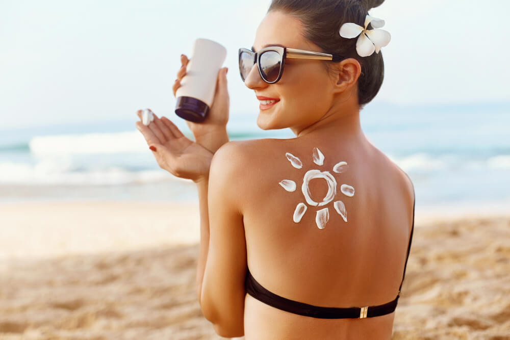 Woman Applying Sun Cream on Tanned Shoulder in Form of the Sun