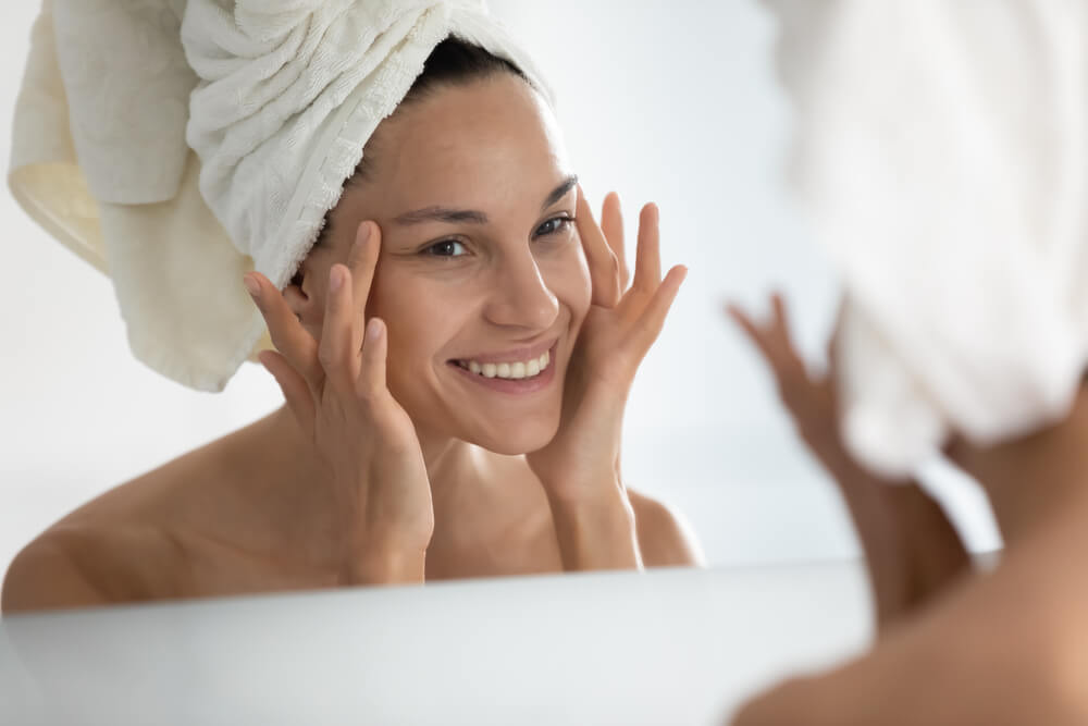 After Beauty Home Spa Procedure Woman Looks at Perfect Skin in Mirror Touch Face Feels Satisfied