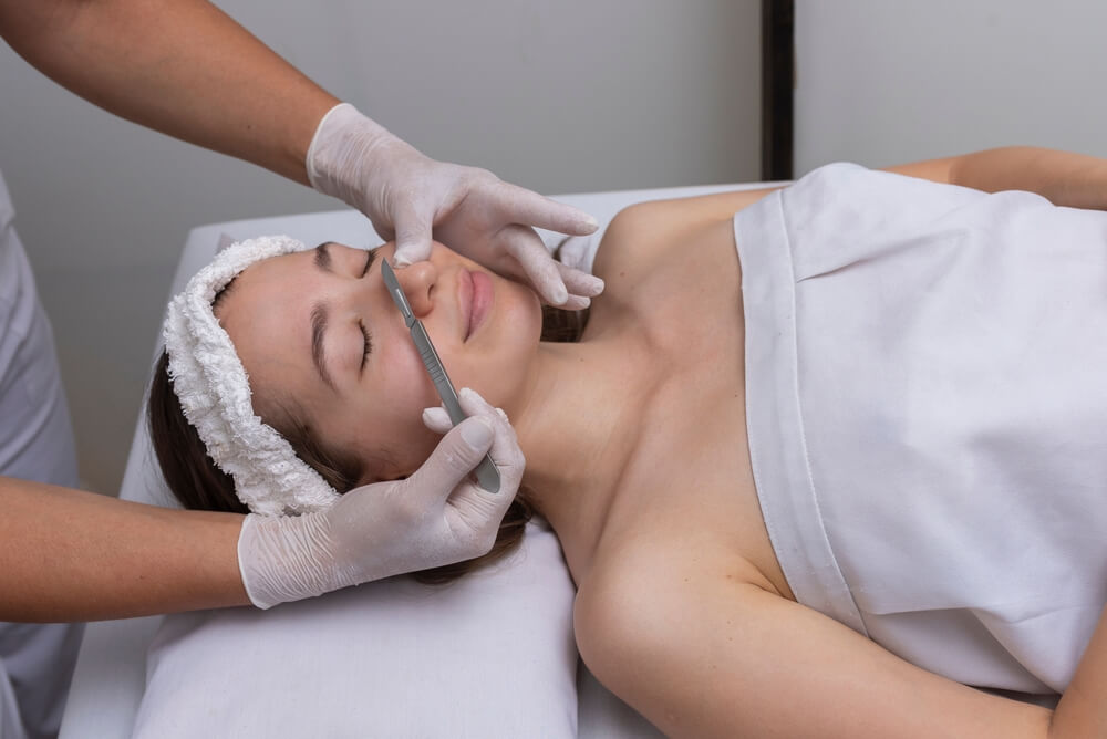 Young Woman Lying on a Stretcher in an Aesthetic Center Performing Beauty Treatment and Facial Aesthetics With Dermapen and Dermaplaning Techniques