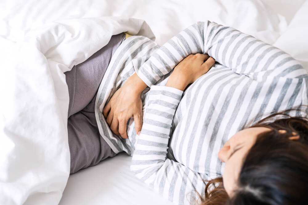 Young Woman Having Stomach Ache on the Bed.