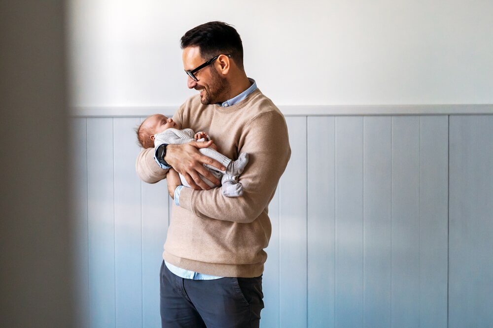 Portrait of young father holding his newborn baby