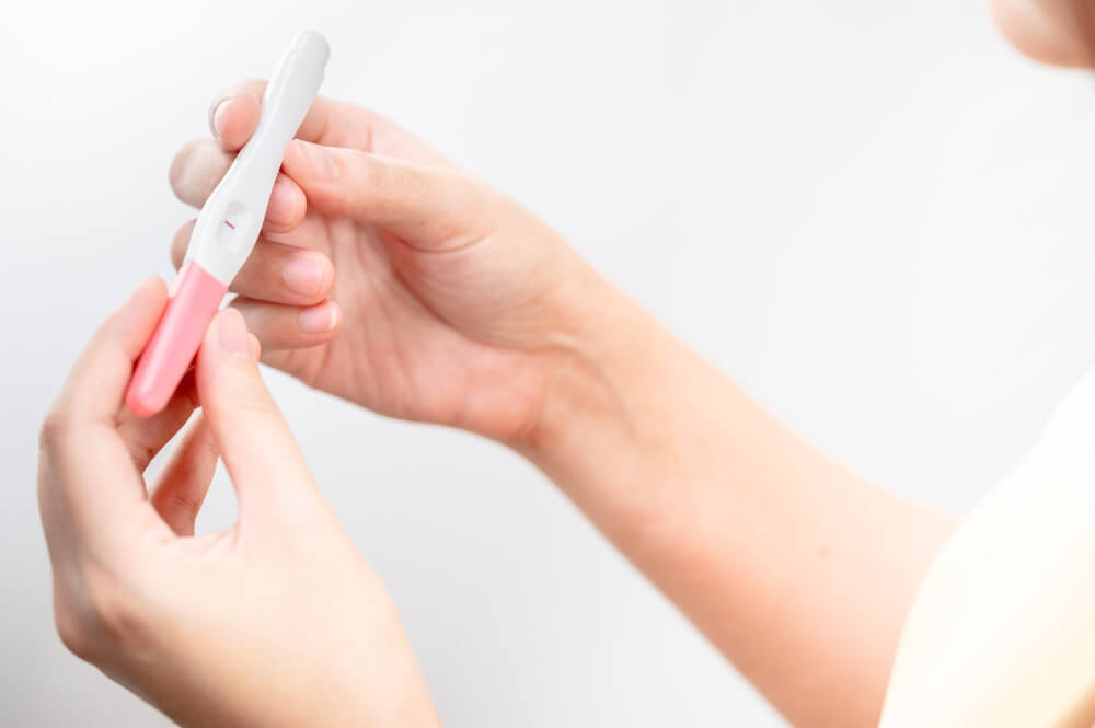 A woman holding pregnancy test results, female health problems and infertility