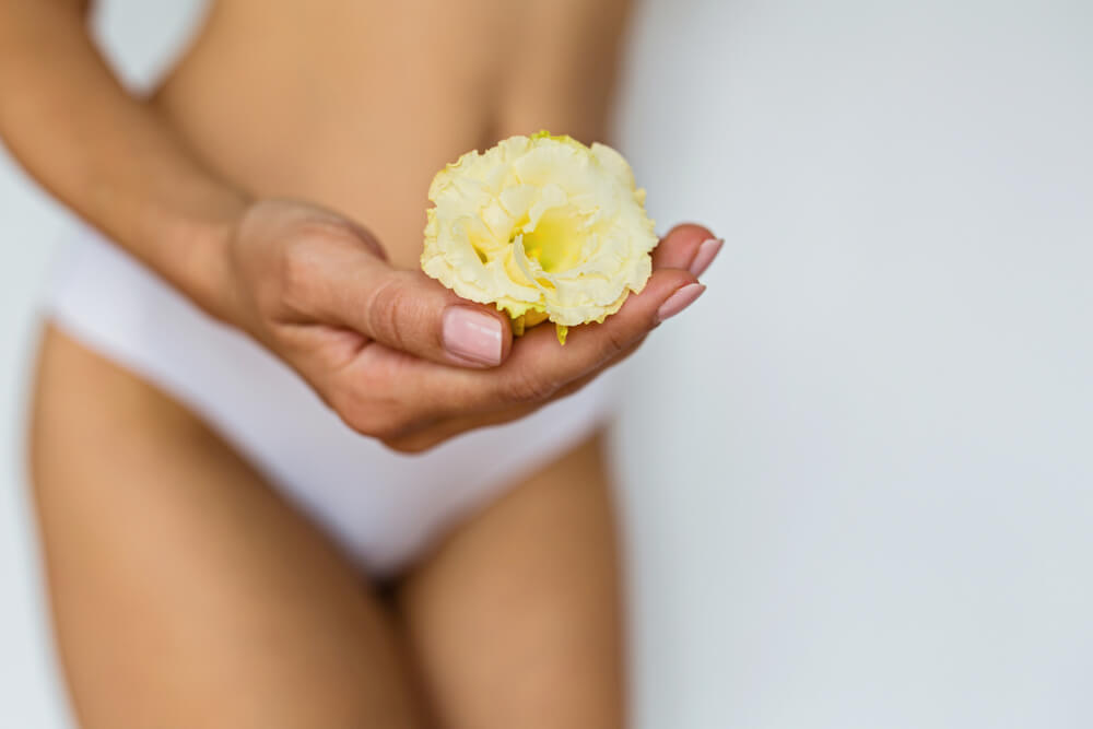 Woman holding flower in front of her private parts