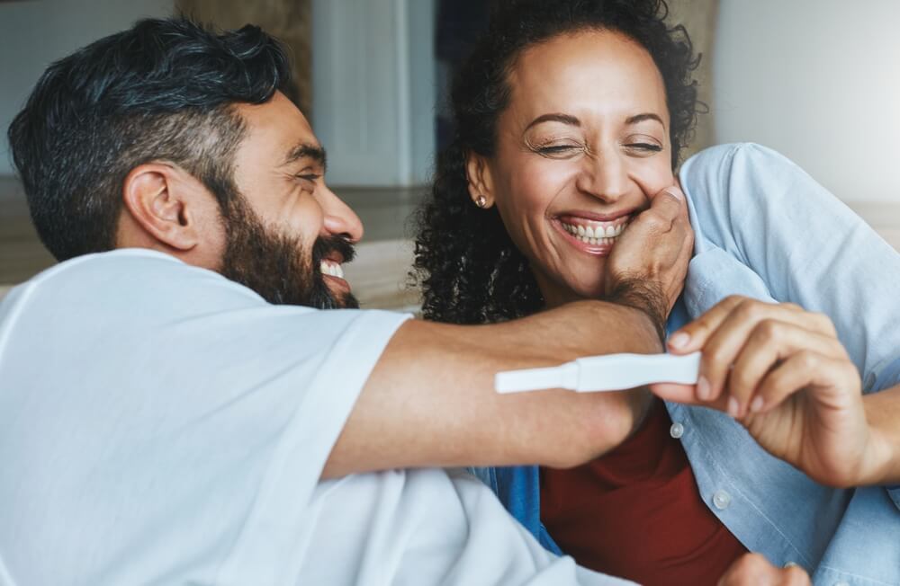 Happy couple, excited and smiling for pregnancy test