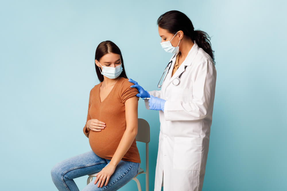 Nurse in Face Mask Making Vaccination for Pregnant Female Patient for Antiviral Immunization During Pregnancy